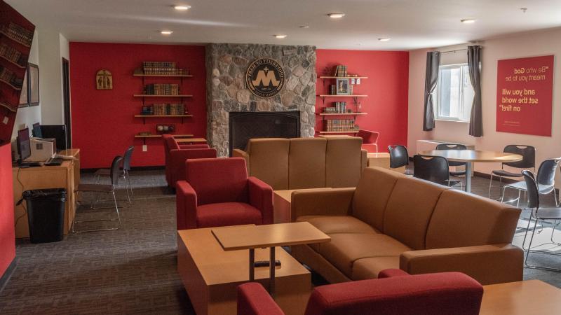 Living room set up in Roers Hall featuring a fireplace, couches, and tables.